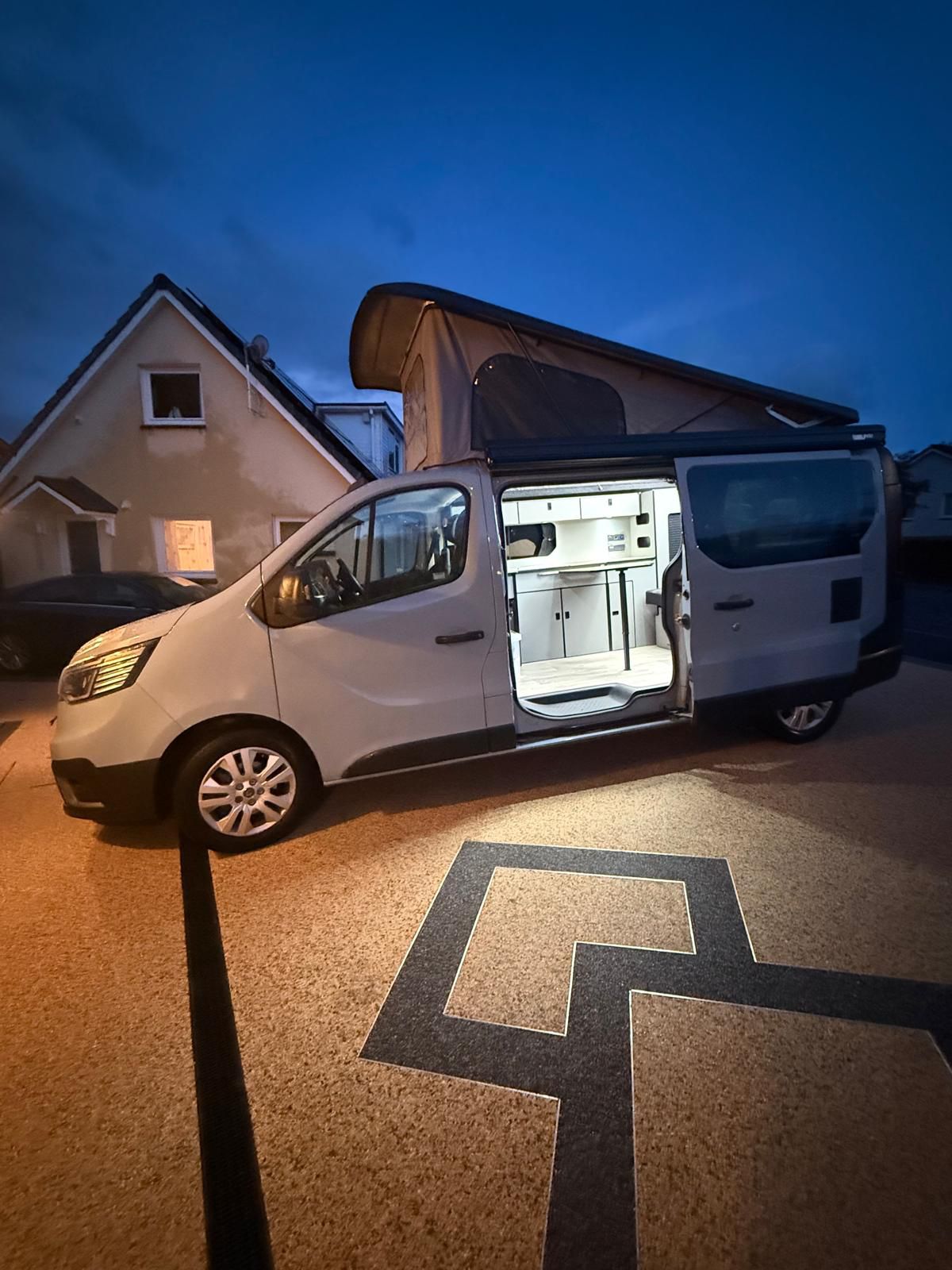 Maisie-Moo with side door open and pop-top up on a driveway at dusk