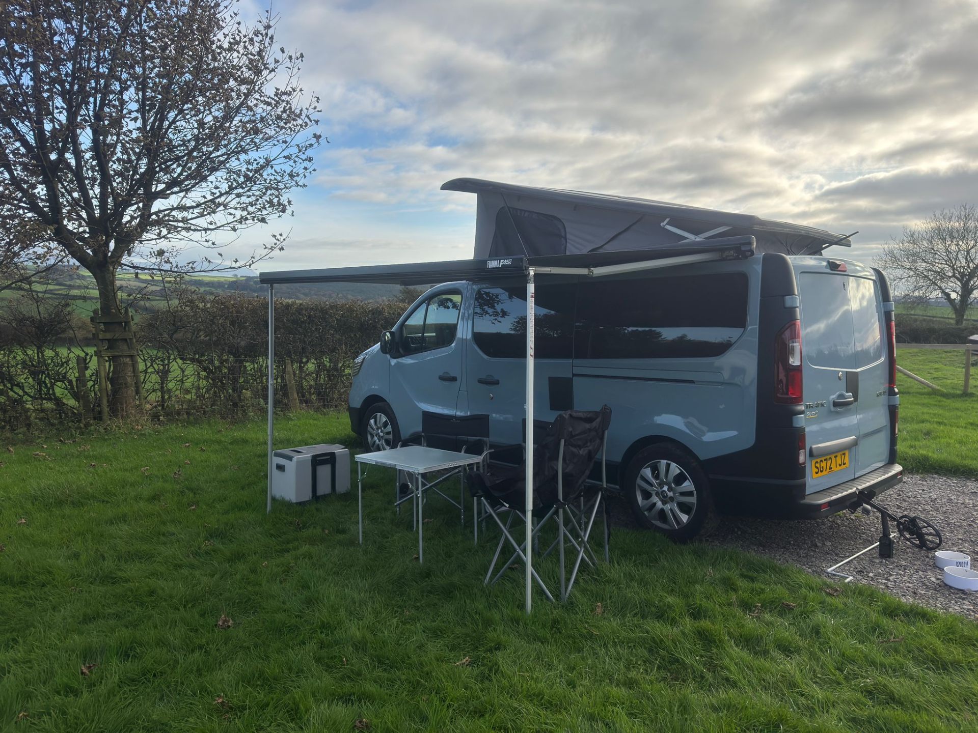 Maisie-Moo with awning out and table set up in a countryside field